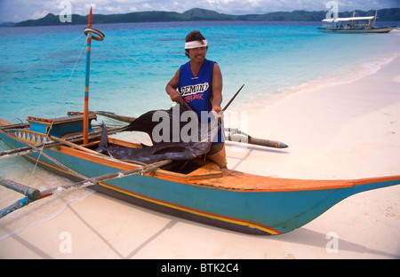 Un pescatori visualizza un marlin pesce catturato da un piccolo lavoro di pescatori da un piccolo fatto in casa canoa outrigger nelle Filippine. Foto Stock