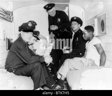 E poliziotti feriti African American uomo dentro di polizia, ambulanza durante il 'Zoot Suit' tripudio di 1943. In base etnica ostilità, provocato dall'urban hipster 'Zoot Suit' fashion, portato a violenti attacchi sui civili di giovani da mobs di servizio agli uomini. Los Angeles, Giugno 1943 Foto Stock