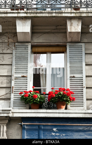 Affascinante vecchio legno bianco anta di finestra con bianco aperto le persiane e pot di luminoso rosso dei gerani sul davanzale Rue de Poissy Parigi Foto Stock