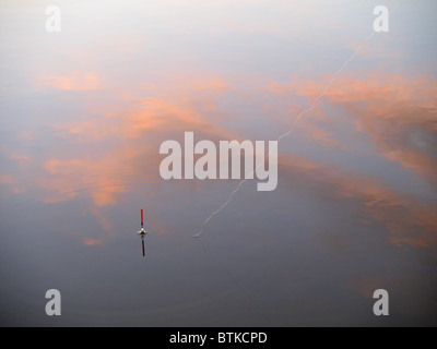 La pesca galleggiante nelle acque che riflettono il tramonto rosso, REGNO UNITO Foto Stock