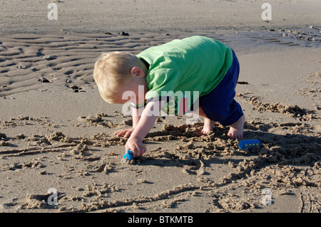 Un giovane ragazzo giocando su una spiaggia Foto Stock