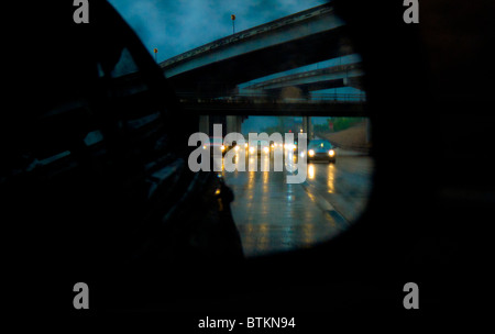 Il traffico di Freeway riflessa in auto specchio retrovisore durante la pioggia torrenziale storm in Houston, Texas, Stati Uniti d'America Foto Stock