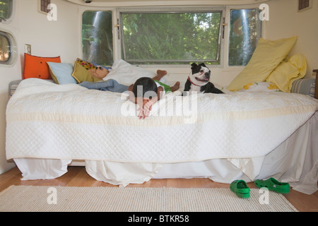 Ragazzo e cane sul letto in camper Foto Stock