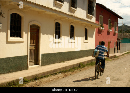 Ragazzo in sella ad una bicicletta passato case restaurate in stile coloniale spagnolo città di Gracias Lempira,, Honduras Foto Stock