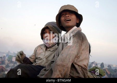 Due giovani bambino operaio ragazze sono rilassanti in un inquinata discarica di rifiuti in Cambogia. Foto Stock