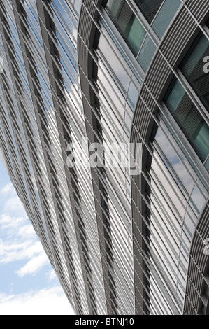 Vista della curva esterna edificio per uffici a guardare in alto verso il blu e il cielo nuvoloso Foto Stock