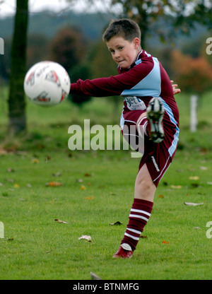 9-10 anno vecchio ragazzo calci un calcio nel parco Foto Stock