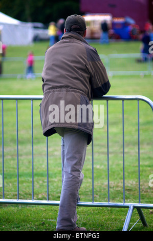 Uomo appoggiato sulla recinzione di sicurezza barriera Foto Stock