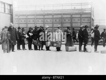 Foto d'epoca circa 1911 degli immigrati in coda per essere elaborati ad Ellis Island in New York. Foto Stock