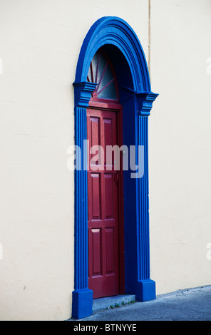 Una porta rossa in un blu del telaio della porta in una parete bianca a Siddal, vicino a Galway, Irlanda. Foto Stock