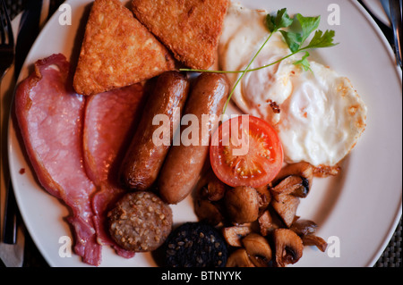 La prima colazione in stile irlandese, con in bianco e nero il budino, uova fritte, pancetta, salsicce, pomodori grigliati e funghi. Foto Stock