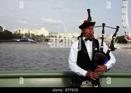 Uomo in abiti tradizionali con la cornamusa scozzese su un ponte di Londra Foto Stock