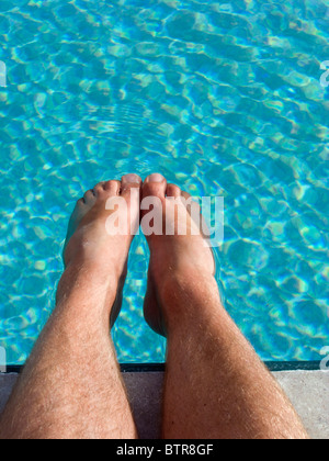 Ritratto di auto di un uomo imbibire i suoi piedi in una piscina. Foto Stock