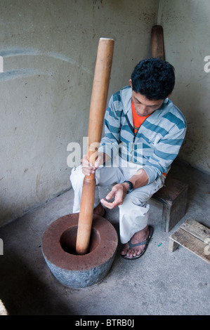 La mangusta Lewak o caffè macinato in grandi pestello e mortaio dal lavoratore in Bali Indonesia sulla piantagione di piccole dimensioni Foto Stock