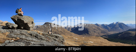 Hillwalker poggiante su una roccia e guardando attraverso Glen Etive a Ben Starav. Foto Stock