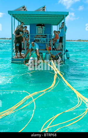 I turisti in Mauritius discendente dalla piattaforma per la famosa passeggiata sottomarina ancorato sulla barriera corallina vicino alla Grande Baie Foto Stock