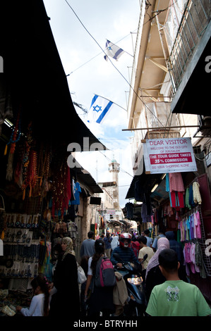 Un insediamento israeliano vola bandiere sopra un minareto e marketplace nel quartiere musulmano della città vecchia di Gerusalemme. Foto Stock