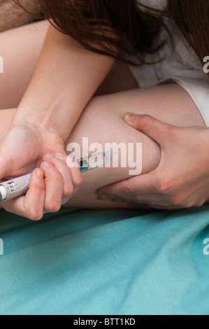 Giovane persona diabetica dando loro una lantus iniezione di insulina nella gamba per il trattamento di un tipo di diabete Foto Stock