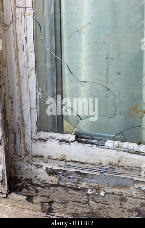 Rotto il vetro della finestra e sfald vernice sulla casa abbandonati Foto Stock