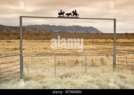 Ranch gate sul deserto del Chihuahuan vicino presidio, Texas, Stati Uniti d'America con la Sierra grande massiccio in tutta Rio Grande in Messico in dist, inverno Foto Stock