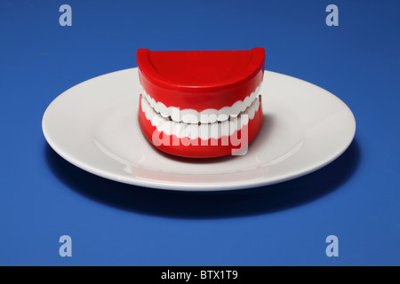 Un set di gomme in plastica e denti su un bianco piastra cena Foto Stock