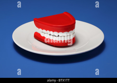 Un set di gomme in plastica e denti su un bianco piastra cena Foto Stock