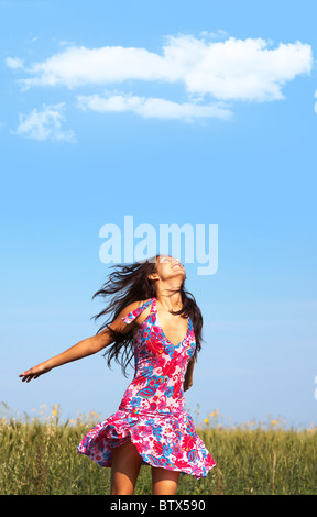 Foto di lieta ragazza in abiti colorati per godersi la vita nel prato di grano in estate Foto Stock