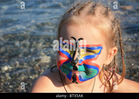 Bambino il volto dipinto come butterfly al mare Foto Stock