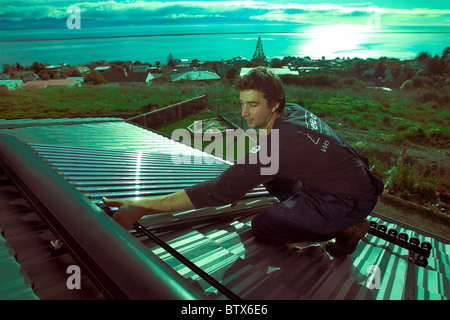 Artigiano qualificato installazione solare di acqua calda sistema a una casa, Nelson, Nuova Zelanda, la città con la più alta ore di sole. Foto Stock