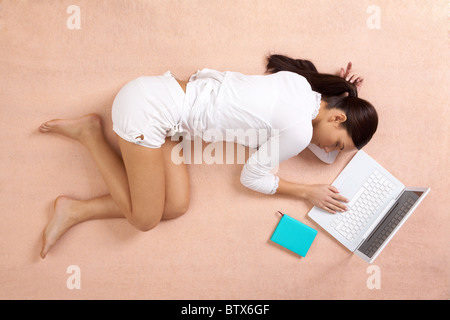 Vista dal di sopra della pacifica ragazza avente un pisolino con laptop nelle vicinanze Foto Stock