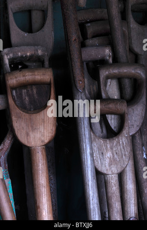 Una collezione di spade in legno e maniglie a forcella con altri attrezzi da giardino in un capannone. Novembre 2010 Foto Stock