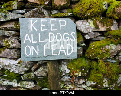 Un segno scritto su ardesia che chiede cani tenuti in testa nel Lake District Park, Cumbria, Inghilterra. Foto Stock