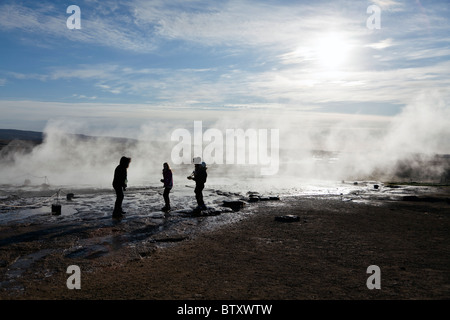 I turisti a guardare l'eruzione di Strokkur geyser nel sud-ovest dell'Islanda. Foto Stock