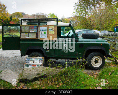 Un National Trust Land Rover Defender in un parcheggio a Elterwater nel Parco Nazionale del Distretto dei Laghi con un display di reclutare nuovi membri. Foto Stock