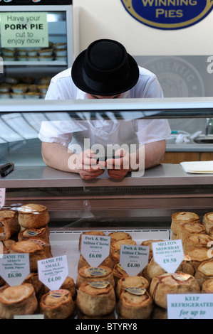 Butcher nel mercato di Borough tramite telefono Foto Stock