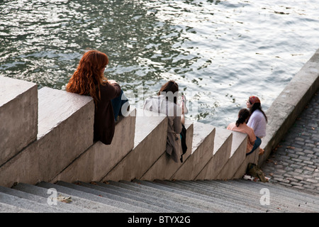 Quattro estranei giovani donne geometricamente disposti contro uno sfondo di scintillanti acque del fiume Senna a Parigi Foto Stock