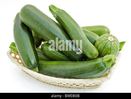 Fresco verde di piccole dimensioni le zucchine in un wattled cestello di piccole dimensioni Foto Stock