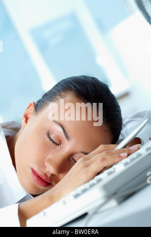 Immagine della giovane imprenditrice di dormire sul posto di lavoro con la sua testa sulla tastiera Foto Stock