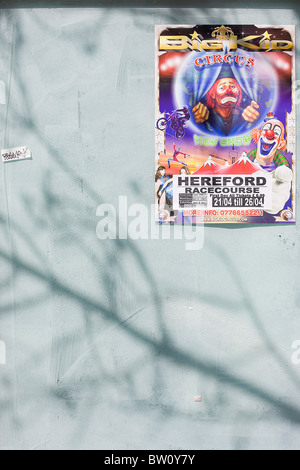 La faccia triste di un clown viene visto su un poster di circo accanto a un pub locale annuncio che sono incollati su un ex high street business Foto Stock