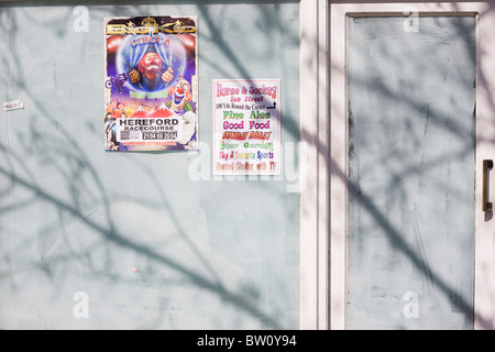 La faccia triste di un clown viene visto su un poster di circo accanto a un pub locale annuncio che sono incollati su un ex high street business Foto Stock