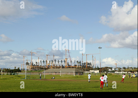 Vista del Green Point Stadium in costruzione, con una partita di calcio in corso in primo piano Foto Stock