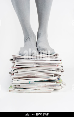 Uomo in piedi su una pila di vecchi giornali, Riciclaggio Foto Stock