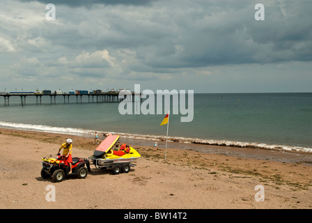 Bagnino RNLI su di una moto quad tirando un getto sci dietro a Teignmouth beach con pier in background, Devon England Regno Unito 2010 Foto Stock