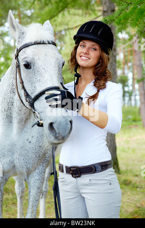 Immagine di felice femmina con cavallo di razza nelle vicinanze Foto Stock