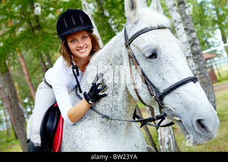 Immagine di felice jockey femmina sul cavallo di razza in esterno Foto Stock