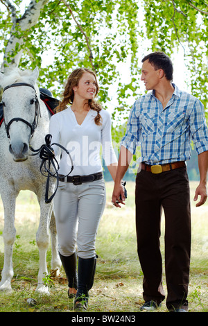 Immagine di donna felice circondato da cavallo di razza pura e la sua fidanzata durante il cammino Foto Stock