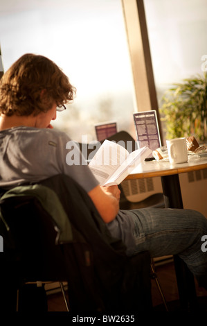 Uno studente la lettura di un libro di testo in cafe di Aberystwyth University Wales UK Foto Stock