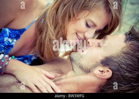 Coppia giovane giacciono abbracciando Foto Stock