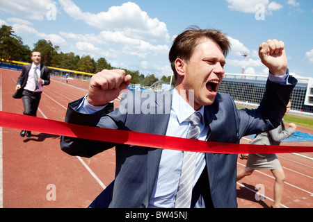 Foto di happy businessman Attraversamento linea di finitura durante la gara Foto Stock