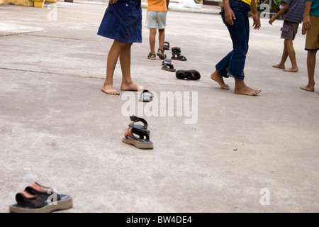 Un gruppo di giovani i bambini stanno giocando a un tradizionale gioco di strada con pantofole in Vientiane, Laos. Foto Stock